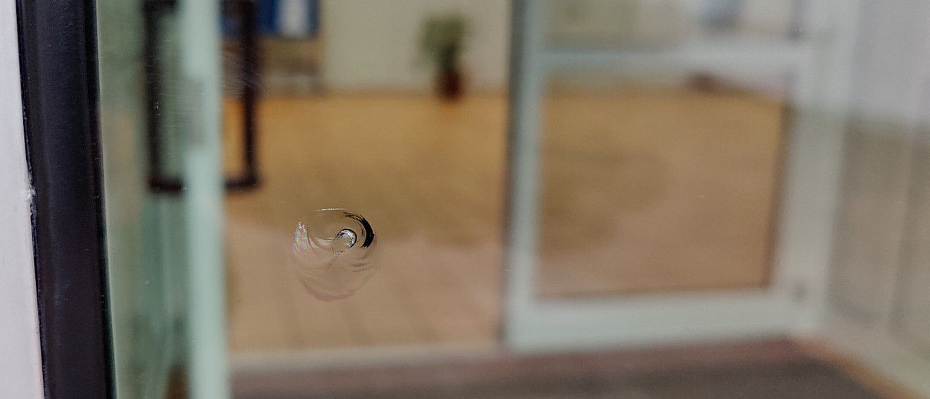 Einschussloch im Glas der Türe